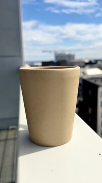 Coffee Cup on Balcony Railing on Sunny Summer Day