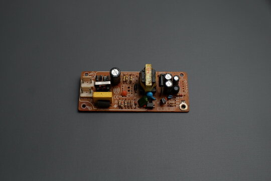 An electronic power supply circuit board module with various components mounted on it, set against a dark gray background.