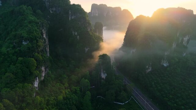 Aerial view of a scenic road through limestone karst mountains and morning mist in Krabi, Thailand