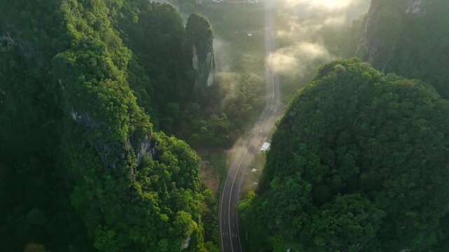 Aerial view of a scenic road through limestone karst mountains and morning mist in Krabi, Thailand