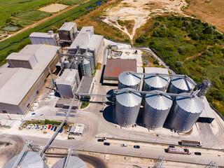 Industrial facility with grain silos and processing buildings located in a rural area during daytime © DSMT