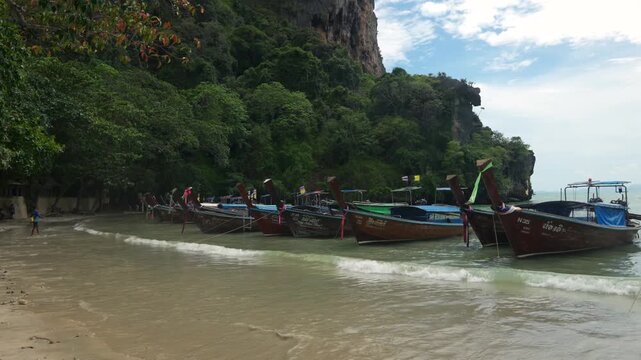 Beautiful tropical Railay beach with limestone cliffs and traditional longtail boats in Krabi, Thailand.
