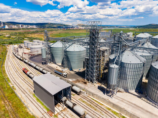 Grain storage facility with silos and train tracks in a rural area on a bright day © DSMT