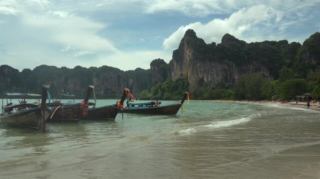Beautiful tropical Railay beach with limestone cliffs and traditional longtail boats in Krabi, Thailand.