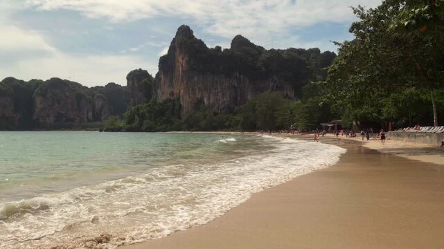 Beautiful tropical Railay beach with limestone cliffs and traditional longtail boats in Krabi, Thailand.