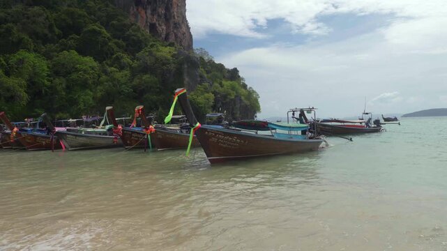 Beautiful tropical Railay beach with limestone cliffs and traditional longtail boats in Krabi, Thailand.