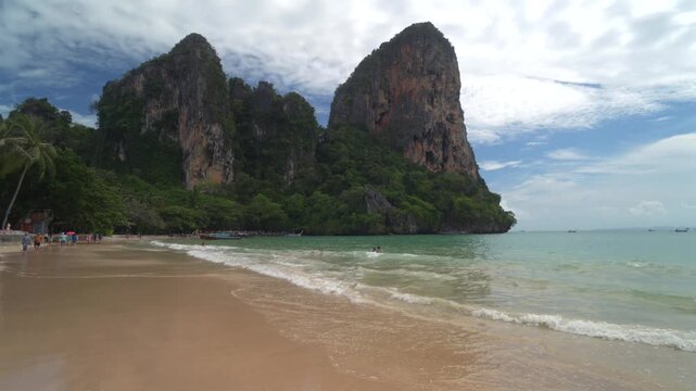 Beautiful tropical Railay beach with limestone cliffs and traditional longtail boats in Krabi, Thailand.