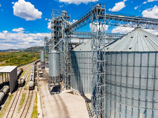 Grain storage facility with silos and railway tracks in an industrial area under blue skies © DSMT