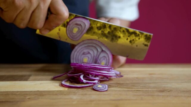 Fresh red onion being sliced with a yellow vegetable peeler on wooden surface