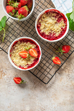 Traditional English crumble cake with strawberry with backed topping  of oatmeal flour, butter and sugar in a baking dish on a stone countertop. Top view flat lay background. Copy space.