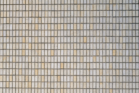 Small concrete tiles form a repeating grid on an urban building facade