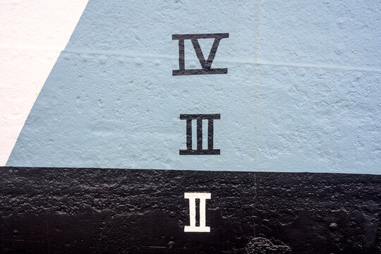 Roman numerals IV, III and II painted on a textured painted wall