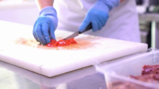 Raw meat chunks inside clear plastic container on preparation surface
