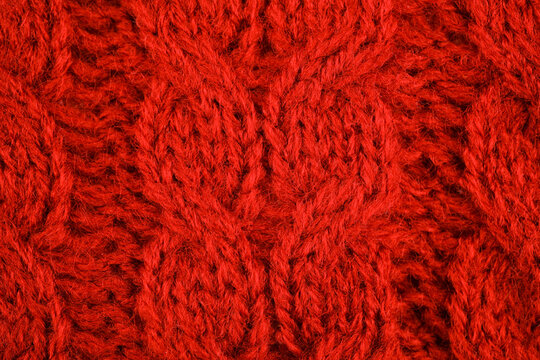 Close up of a red knit fabric with a cable pattern