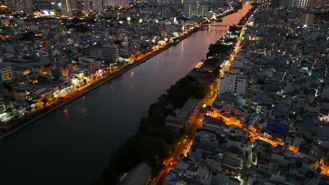 Panoramic drone shot of Ho Chi Minh City skyline, Ben Nghe Canal, and city lights at dramatic red sunset in District 4, Saigon Vietnam