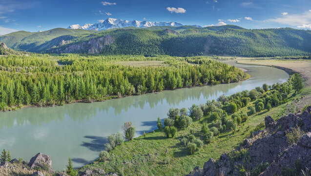 Mountain valley with a river, snow-capped peaks and green forests, summer travel