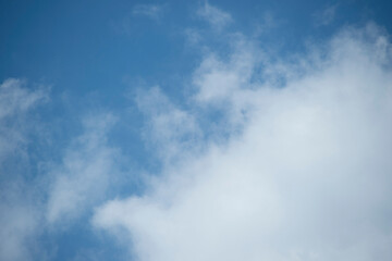 Obraz premium Soft white cumulus clouds float across a bright blue daytime sky. The clear atmosphere provides ample copy space for design projects.