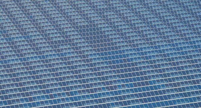 Aerial view of an agrivoltaic greenhouse complex featuring repeating rows of photovoltaic solar panels integrated into greenhouse rooftops in Saulce-sur-Rhone, Auvergne-Rhone-Alpes, France.