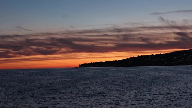 A colorful sunset illuminates the calm sea and dark coastal silhouette of the Bay of Naples. Such breathtaking maritime landscapes inspire romantic travel and deep appreciation for Italian nature.