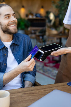 Smiling man paying for food in a cafe by credit card