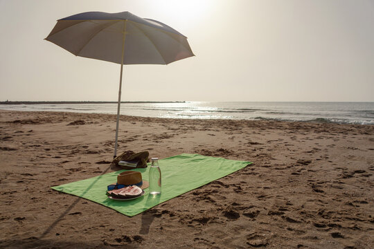 Beach umbrella with fresh watermelon plate hat sunglasses and water