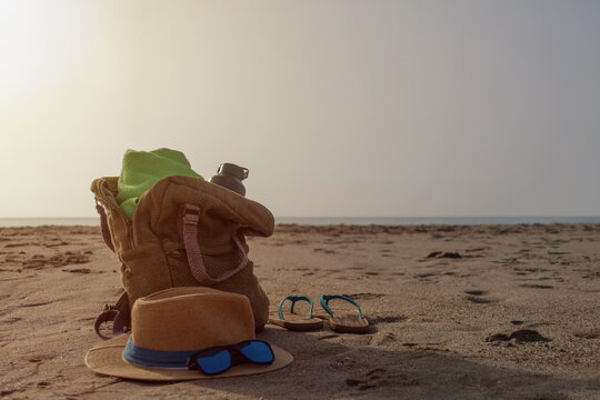 Beach backpack with towel water bottle hat sunglasses and flip flops