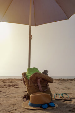Beach umbrella with backpack towel water bottle hat sunglasses and flip flops