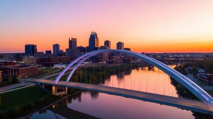 Obraz premium A vibrant city skyline under a stunning sunset with a reflecting river and modern arch bridge
