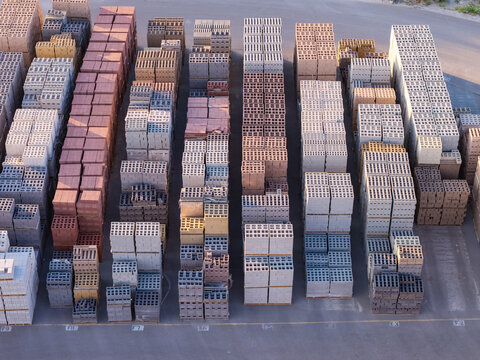 Aerial view of stacked masonry blocks and concrete pavers organized in rows at a construction supply yard in Bluffdale, Utah, United States.