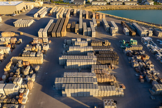 Aerial view of a masonry block loading area with stacks of pavers, retaining wall blocks, and construction materials arranged in rows in Bluffdale, Utah, United States.