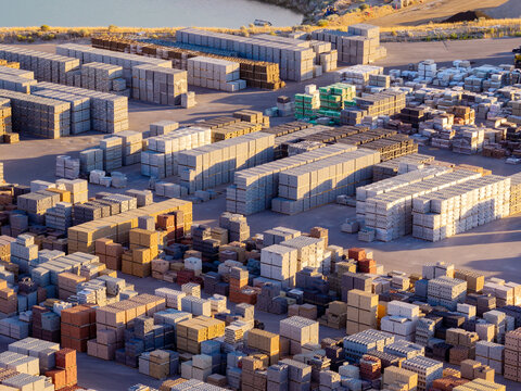 Aerial view of a large industrial storage yard filled with stacked masonry blocks, pavers, and construction materials for retaining walls and fences in Bluffdale, Utah, United States.