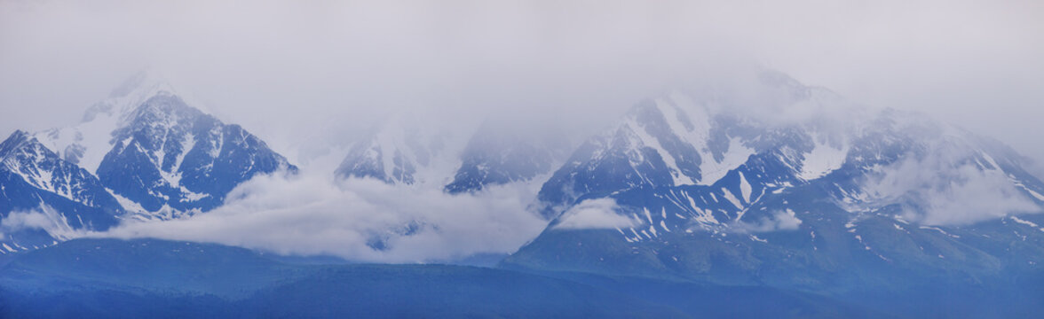 Mountain landscape, snowy peaks in the clouds, panoramic view