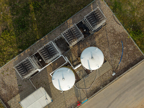 Aerial view of cryogenic gas tanks and cooling towers situated on a gravel industrial site in Poland.