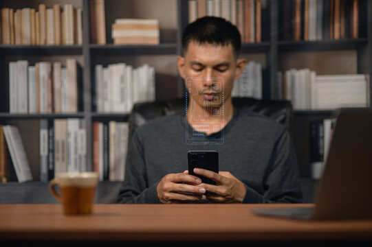 Young Man Using Smartphone at Desk in Modern Library Setting with Bookshelf