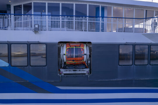 Aerial view of a life raft stored in a recessed compartment on the side of a ferry boat with blue and white stripes in the Netherlands.