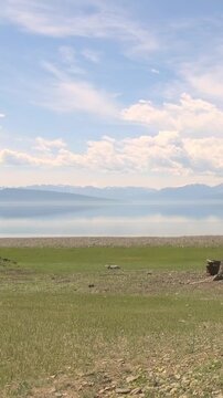 Discover the breathtaking beauty of Lake Khuvsgul in Mongolia. Majestic mountains rise beyond calm waters reflecting the azure sky, surrounded by vibrant, expansive grasslands.