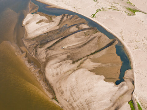 Aerial view of a dry riverbed with exposed sandbanks and shallow water channels caused by a heat wave in Poland.