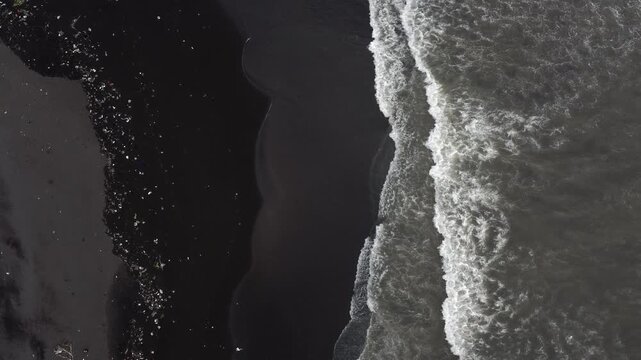 Aerial view of plastic waste washed onto a black volcanic sand beach on Java, Indonesia.