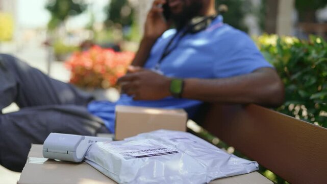 Courier talking to a customer on the phone while waiting to complete a package delivery. Communication, last-mile logistics, and professional delivery service.