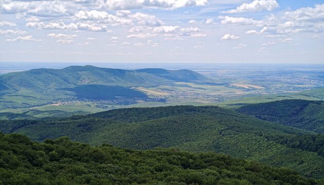 Wide panoramic landscape from the Őr-kő viewpoint overlooking the Felsőt&aacute;rk&aacute;ny Basin and the southern foothills of the B&uuml;kk Mountains under dramatic summer clouds, B&uuml;kk National Park, Hungary.