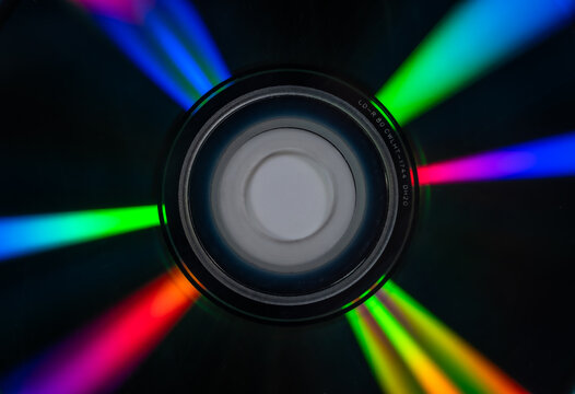 Close up of a compact disc displaying vivid rainbow light reflections across its reflective surface. Concept data storage, digital media, optical technology, nostalgia, background and spectrum.