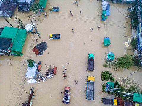 Aerial view of a flooded street in Satkania Upazila with trucks and people wading through muddy water, Satkania Upazila, Chittagong Division, Bangladesh.