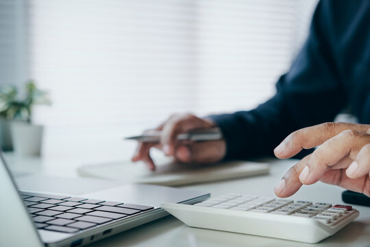Business professional calculating financial data with calculator and laptop, budget planning, accounting analysis, expense management, financial reporting, business finance, bookkeeping, cost control