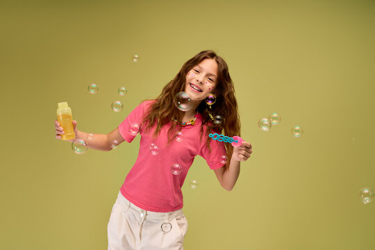 Joyful moments of a little girl blowing bubbles in a bright green room