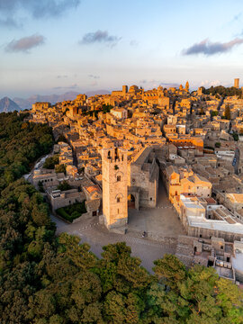 Aerial view of the historic town featuring the bell tower of the Chiesa Madre and stone rooftops bathed in the warm golden light of sunset Erice, Sicily, Italy.