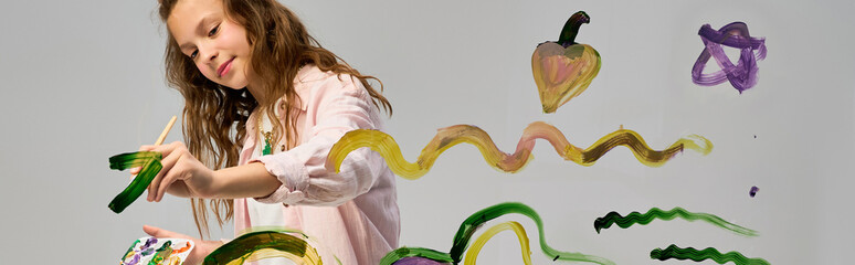 Creative moments of a cute little girl painting colorful swirls and shapes on a blank canvas © LIGHTFIELD STUDIOS