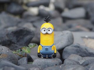 Naklejka premium Indonesia - May 18, 2025 : Mini toy of action figure at outdoor with blurred background. Miniature photography concept design. Minifigure of Minions character from Despicable Me animation film.