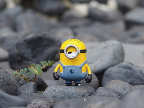 Indonesia - May 18, 2025 : Mini toy of action figure at outdoor with blurred background. Miniature photography concept design. Minifigure of Minions character from Despicable Me animation film.