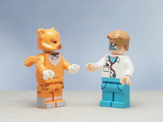 Naklejka premium Indonesia - May 16, 2025 : Mini toy of action figure at table with blurred background. Miniature photography concept design. Minifigure of orange cat and doctor character at clinic. Healthcare concept