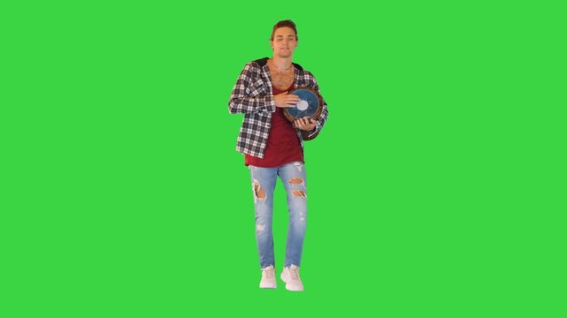 Positive caucasian man walks with and beats his djembe drum on a Green Screen, Chroma Key.